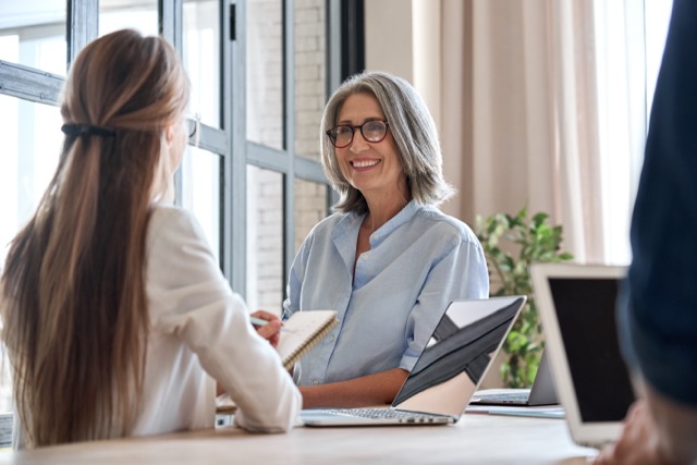 Professor talking to assistant or student at a meeting in office space.