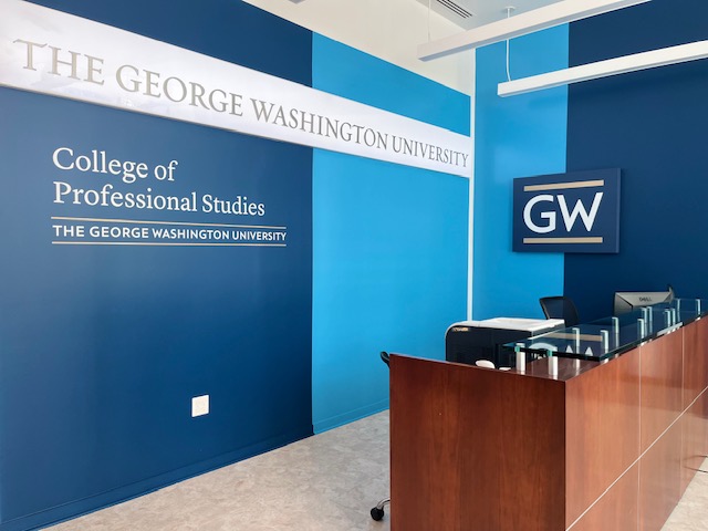 The reception area of the George Washington University College of Professional studies, with the CPS school logo painted onto a blue color-block wall.
